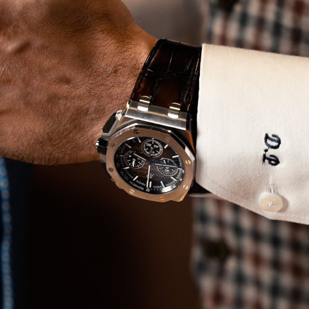 Primo piano di un polso: orologio da uomo e monogramma ricamato sul polsino della camicia